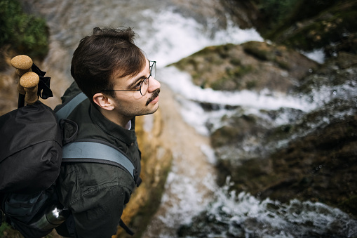 Hiking man explores nature and waterfall