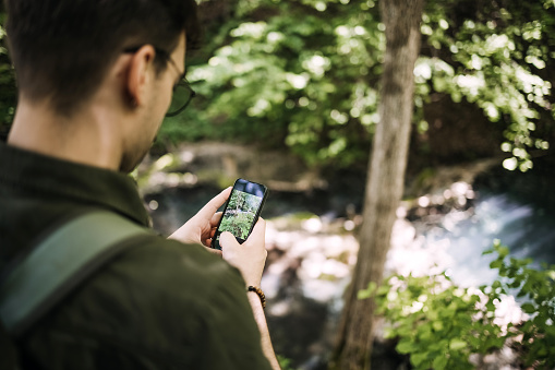 Hiking man uses a mobile phone in the forest