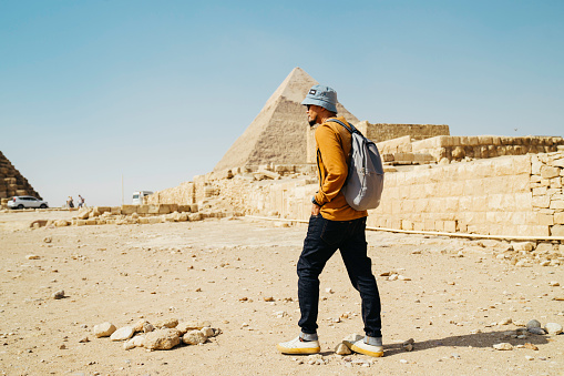 asian man standing on desert on the background of Giza pyramids