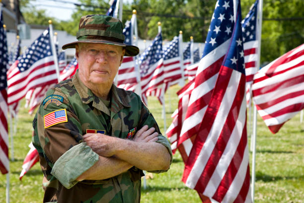 istock Vietnam War Combat Veteran among American Flags looking at camera 1495901687