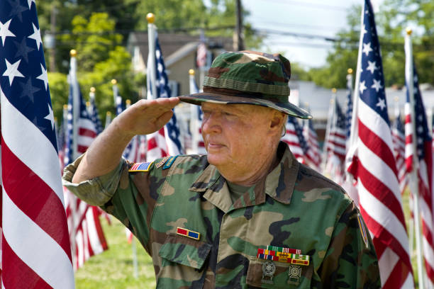 istock Vietnam War Combat Veteran standing with American Flags saluting 1495901720