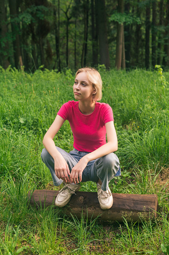 girl teenager squatting on a log in a clearing