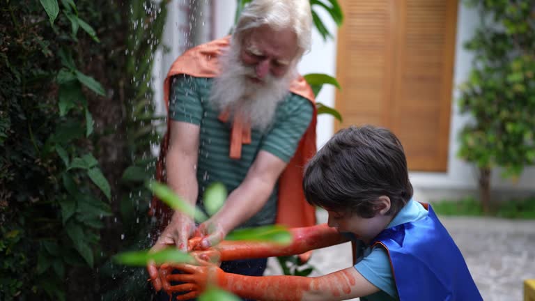 Grandfather and grandson washing hands with paint at home