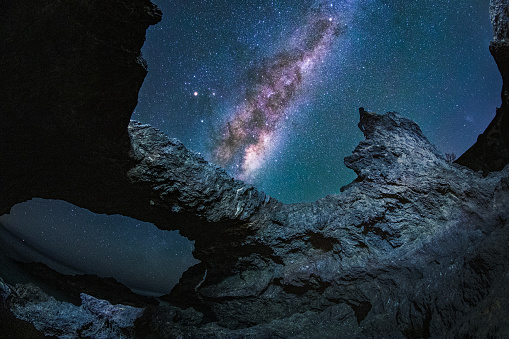 Man gazing into Milky way galaxy at night with unique rock formations in foreground. Shot in Australia.