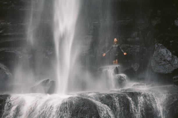istock Happy man standing beneath a large waterfall in the mountains 1495908083