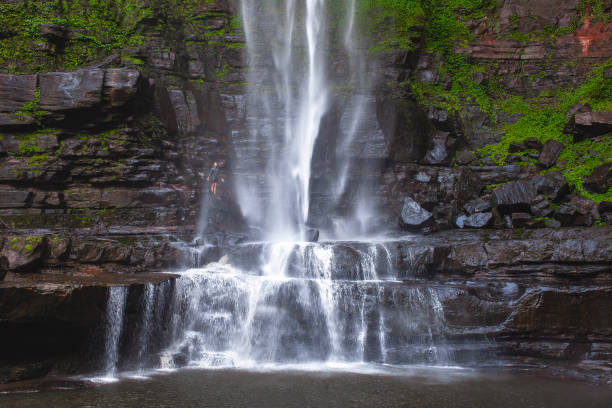 istock Happy man standing beneath a large waterfall in the mountains 1495908137