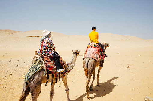Egypt, Cairo, asian couple  tourist riding camel on desert area