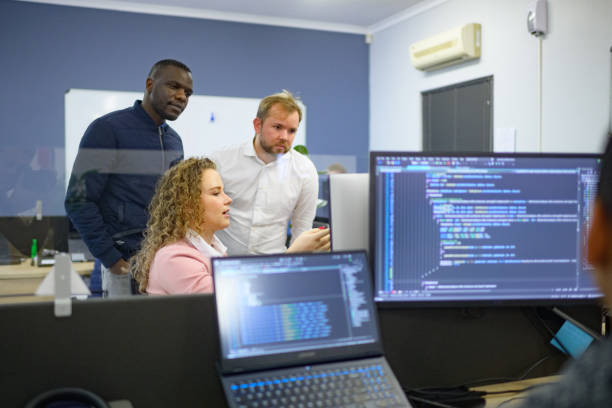 istock Multiracial Group of Computer scientists in discussion with colleagues in an office with code and screens 1495914150