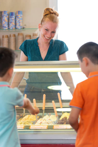 istock Ice cream shop assistant serving two children 1495915559
