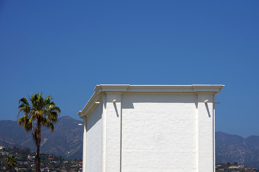 Top of a white windowless building under blue sky