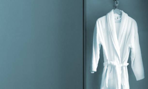 istock Hanger with clean white bathrobe in hotel wardrobe. Space for text 1495921909