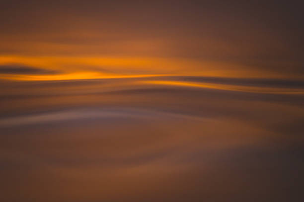 Golden abstract patterns on ocean surface from sunrise stock photo