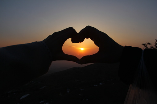 Showing love with hands on the sunset.