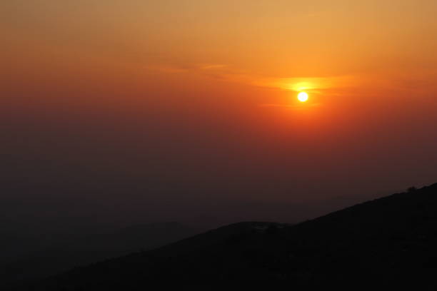 istock Sun at dark orange sunset 
Shining over distant foggy landscape.Sunset scene 1495924621