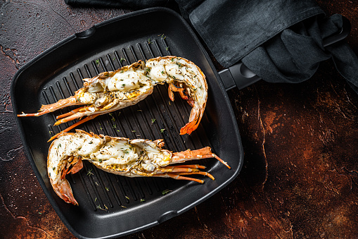 Delicious grilled and sliced Spiny lobster or sea crayfish. Dark background. Top view.