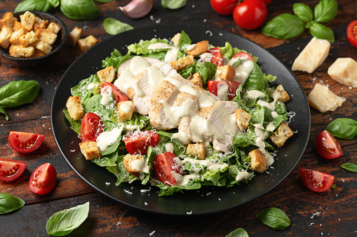 A delicious chicken caesar salad with parmesan cheese, tomatoes, croutons and dressing.