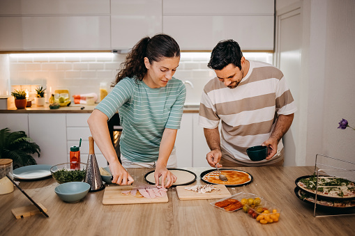 Couple preparing pizza at home in the kitchen