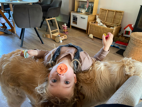 Toddler girl together with and hanging on her dog
