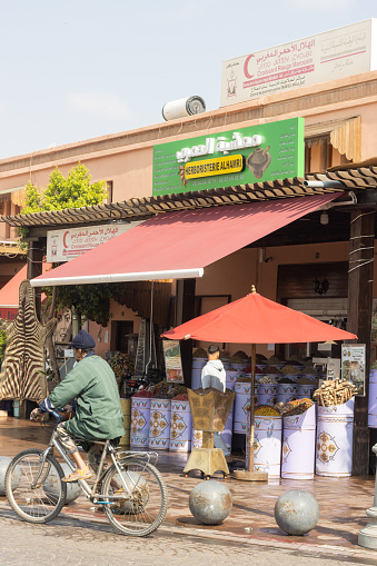 Spice Bazaar at Medina District in Marrakesh, Morocco, with a person cycling past.