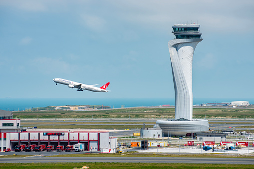 Istanbul, Turkey - June 3, 2023: Turkish Airlines airplane with Air Traffic Control Tower of Istanbul Airport. View of international Istanbul New Airport.