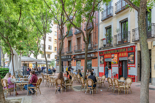 May, 2023. Madrid, Spain - Plaza de Olavide. Springtime  in the city with some young people spending a nice afternoon under shade of trees.