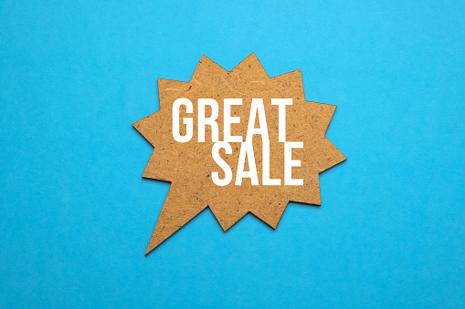 Great sale words on wooden speech bubble on blue paper background. Big sale concept. Copy space.