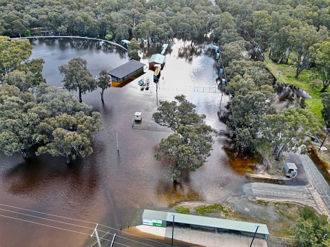 Aerial view of a rural Australian suburb with buildings and trees submerged in floodwaters