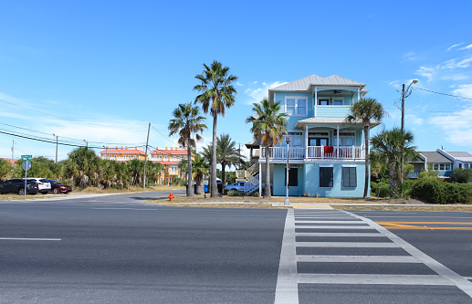 A blue house with palm trees and a crosswalk in Panama City, Florida