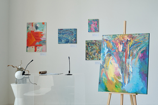 In an art center, visitors looks at the artist's modern art collection. Modern colorful paintings on exhibition.