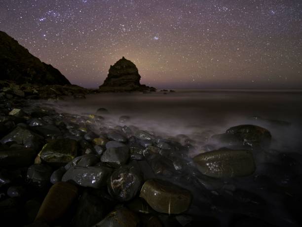istock rocks sit on the shore at night under a sky filled with stars 1495955771