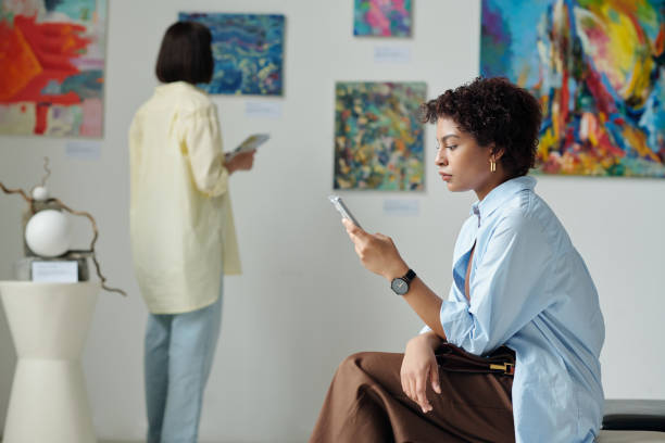istock Woman using smartphone during exhibition in art gallery 1495956159