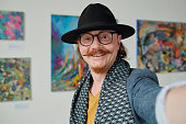 Artist making selfie against his paintings