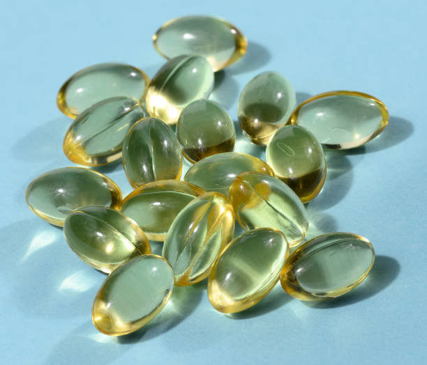 istock Yellow capsules with fish oil on a blue background, close up 1495957555