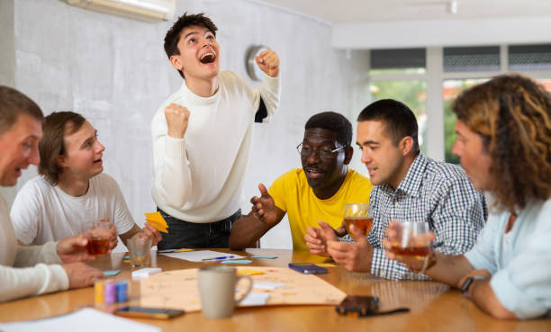 istock Cheerful guy playing board game with male friends 1495963287