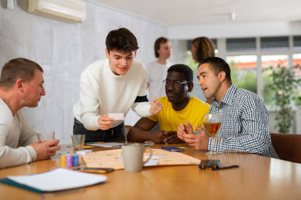 istock Group of enthusiastic men playing board game sitting around table 1495963295