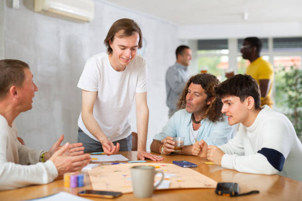 istock Cheerful guy playing board game with male friends 1495963312