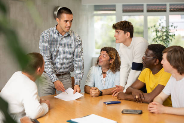 istock Young man instructor explaining the topic to group of guys around the table 1495963519