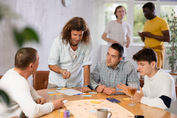istock Excited man playing board game at table with male friends 1495963535
