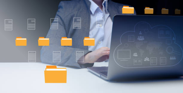 istock Woman sits at a table and works with a laptop. Document management system (DMS). Software for automating archiving and efficient management of information files 1495963536