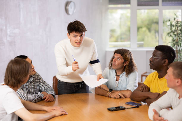 istock Young man instructor explaining the topic to group of guys around the table 1495963539