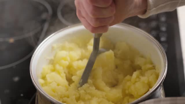 Woman stirring a small pot of Mashed potatoes on the stove.