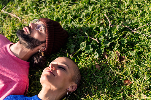 man and woman enjoying a lazy day lying in the lawn, concept of peaceful moment and relax in the nature, copy space for text