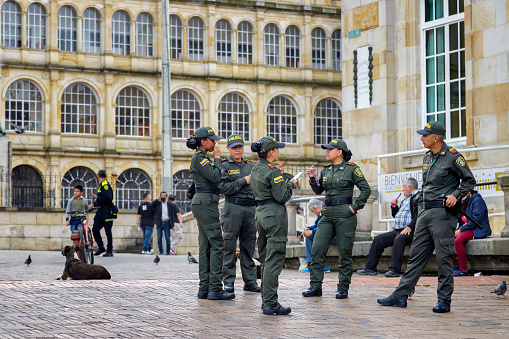 Bogota, Colombia - January 1, 2023: Several police officers chat and eat sweets in Plaza de Bolivar, the main square in Bogota