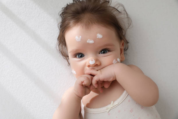 Cute little baby with cream on face in comfortable crib, top view. Space for text