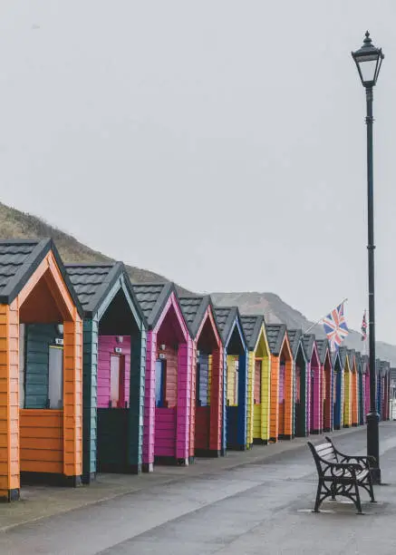 Colourful wooden beach huts at the North Yorkshire seaside town of Saltburn-by-the-Sea on a misty day.
