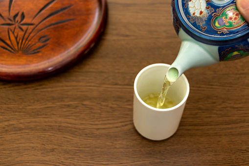 Pouring Japanese tea from a teapot into a cup