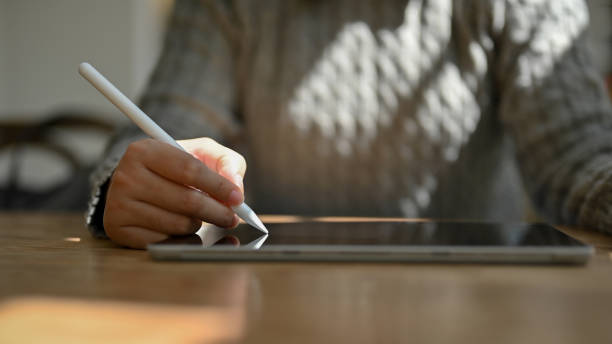 istock Close-up image of a female using a stylus pen to draw or write on her digital tablet 1496002771