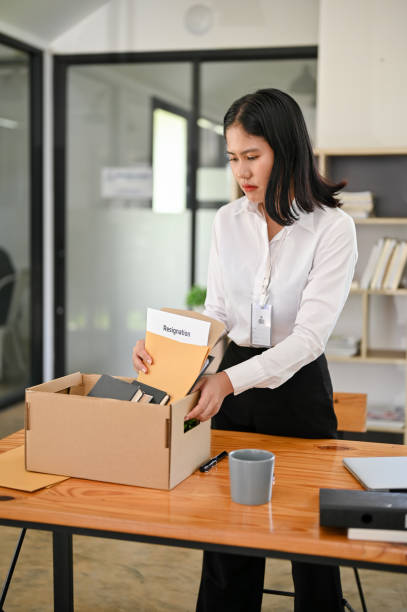 istock A sad and frustrated Asian female office worker packing her stuff, being fired from her boss 1496002924