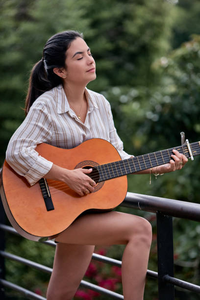istock Hispanic beautiful young woman playing guitar with digital outdoors at home 1496005504