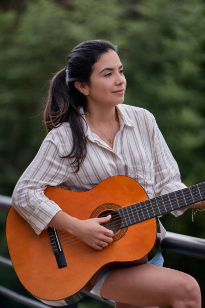 istock Hispanic beautiful young woman playing guitar with digital outdoors at home 1496005512